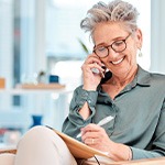 Woman with black glasses smiling while talking on phone