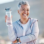 Woman smiling with water bottle on hike outside