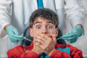 Anxious man at dentist covers his mouth