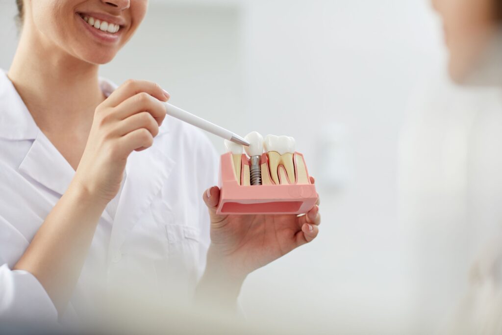 Dentist pointing to sample implant with white pen